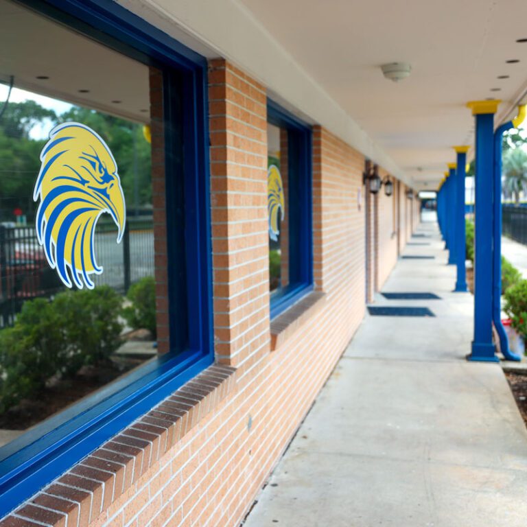 A covered exterior walkway along the elementary building, with the Seacoast eagle logo on a window